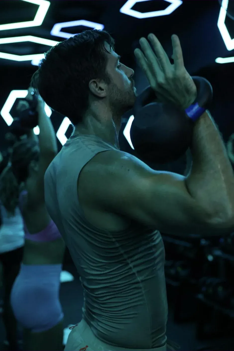 A Booster mid-set with a kettlebell at the chin under the neon of the ReBoost room at CASA BOOST