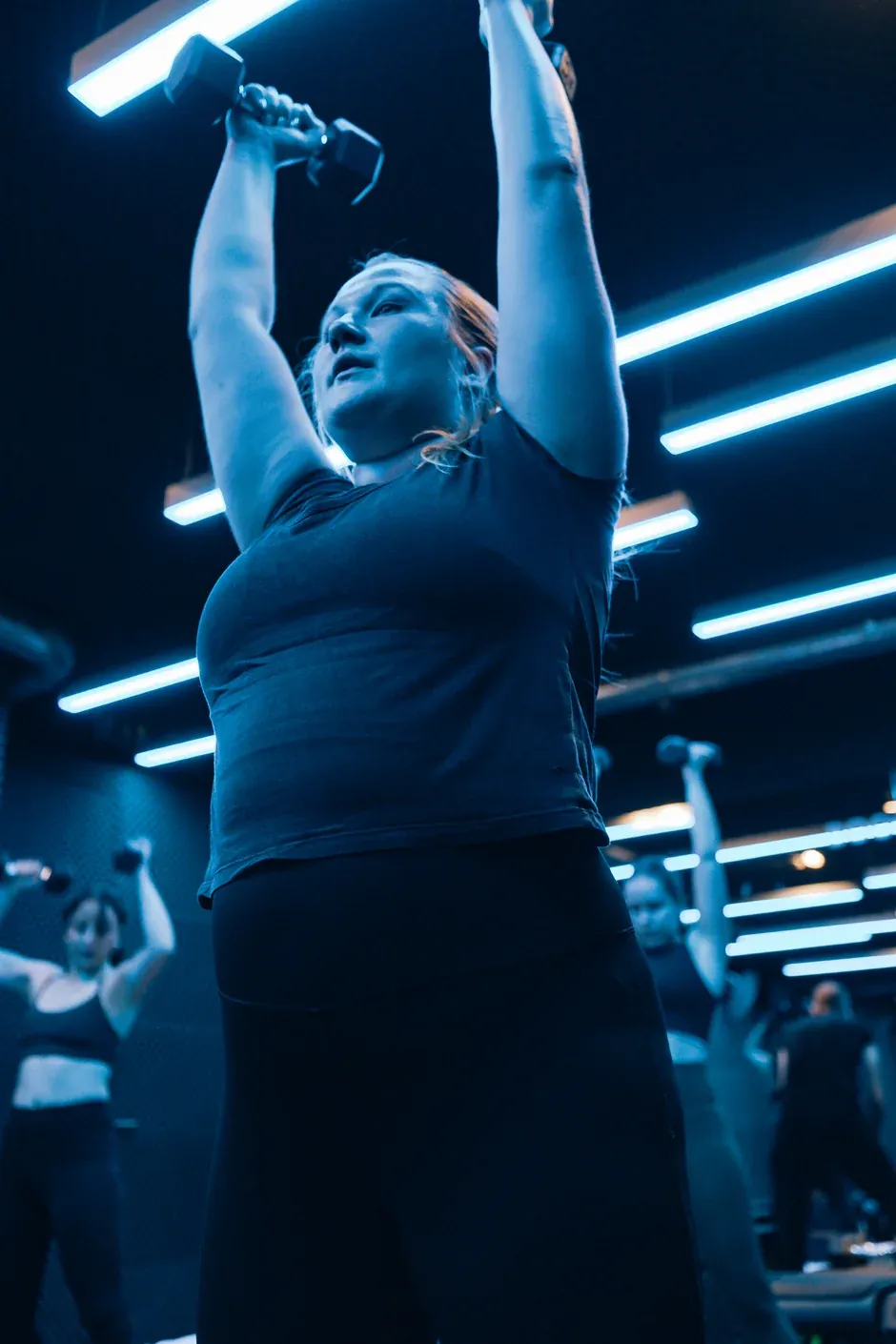 Une membre en haut d&rsquo;un d&eacute;velopp&eacute; au-dessus de la t&ecirc;te pendant un cours de force &agrave; Boost Fitness, CASA BOOST Plainpalais